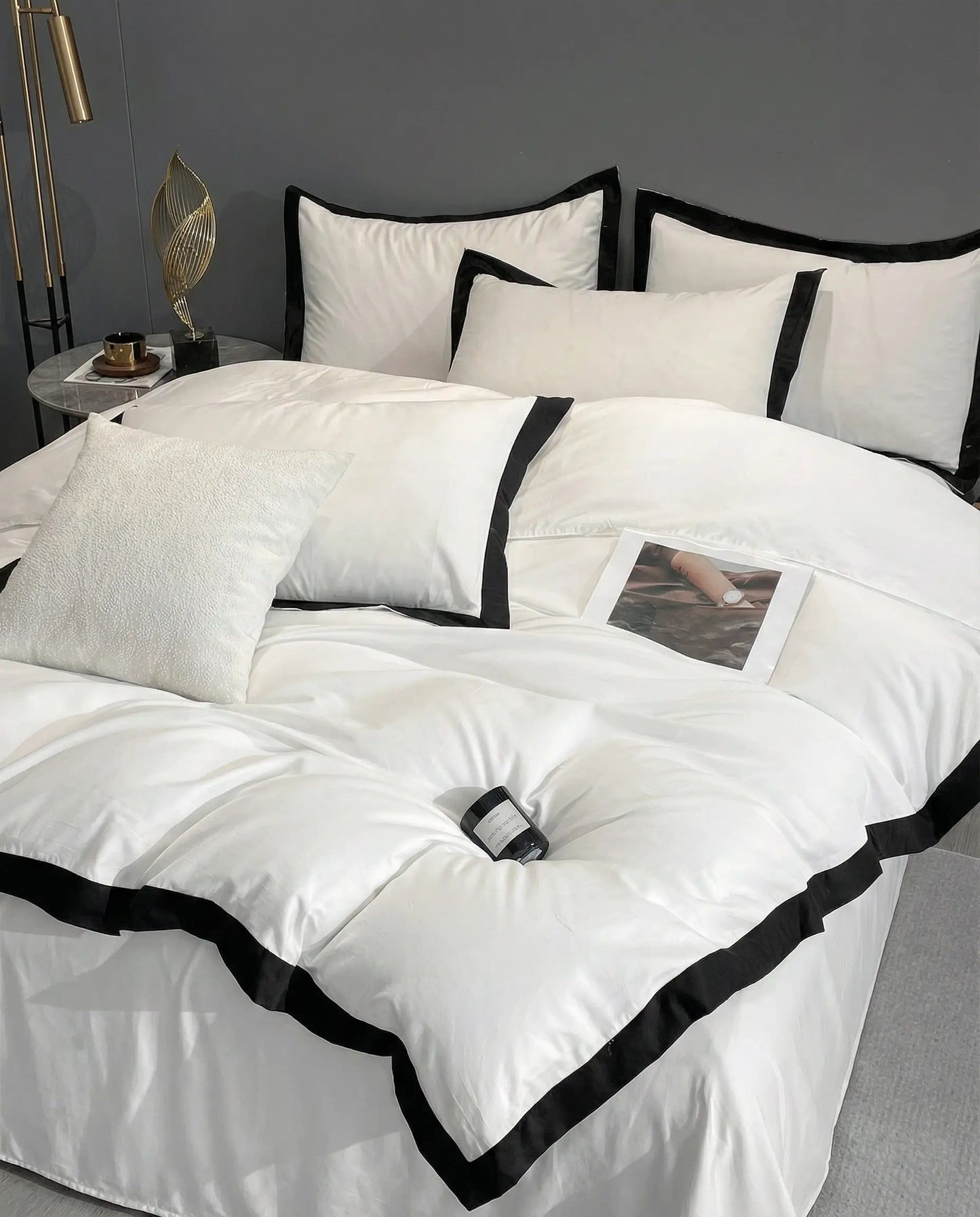 White duvet cover set with black trim styled on bed with layered pillows, modern luxury bedroom decor