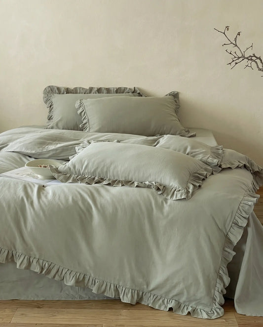 Eucalyptus sage ruffle duvet cover set styled in a warm neutral bedroom with soft luxury bedding and romantic layered pillows