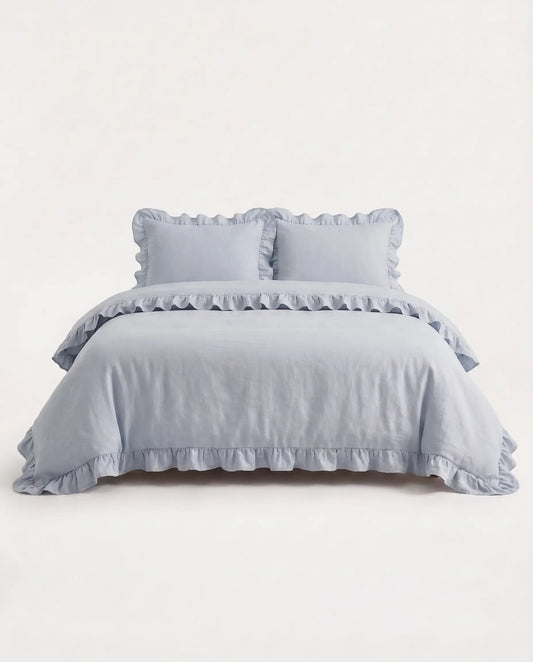 Front-facing studio image of the mist blue ruffle duvet cover set with matching pillowcases and elegant trim