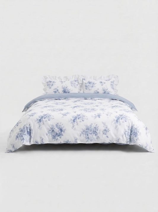 Blue floral ruffled duvet cover set with matching pillow shams styled on bed against clean white studio background