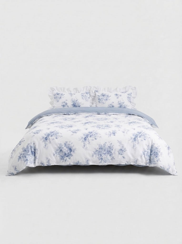 Blue floral ruffled duvet cover set with matching pillow shams styled on bed against clean white studio background