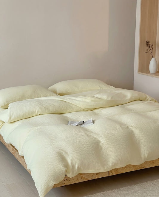 Butter muslin cotton double gauze duvet cover set on a wooden platform bed in soft afternoon light