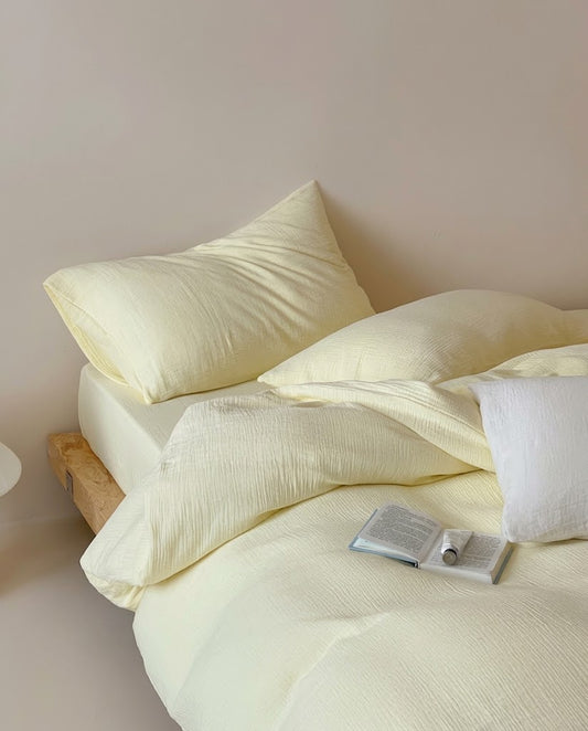 Butter muslin cotton double gauze duvet cover set on a low platform bed with a white pillow and book