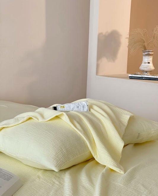 Butter muslin cotton double gauze duvet cover draped over a matching pillowcase beside a dried grass vase