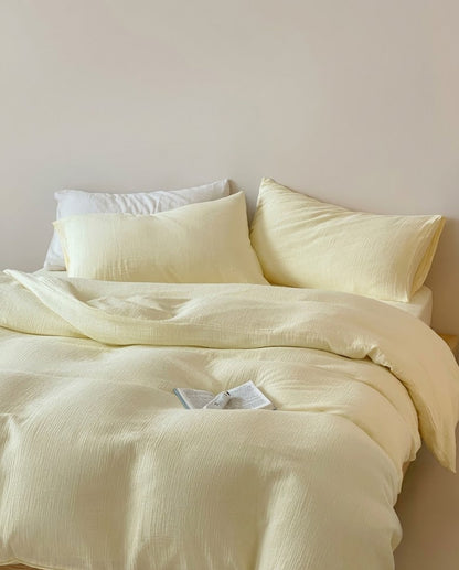 Butter muslin cotton double gauze duvet cover and pillowcases on a bed with a white pillow and open book