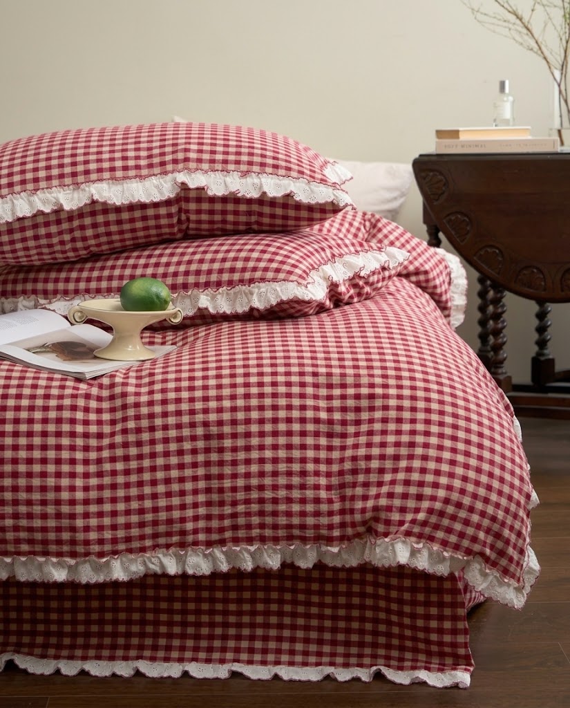 Side view of a gingham duvet cover with ruffled hem over a matching sheet with eyelet trim