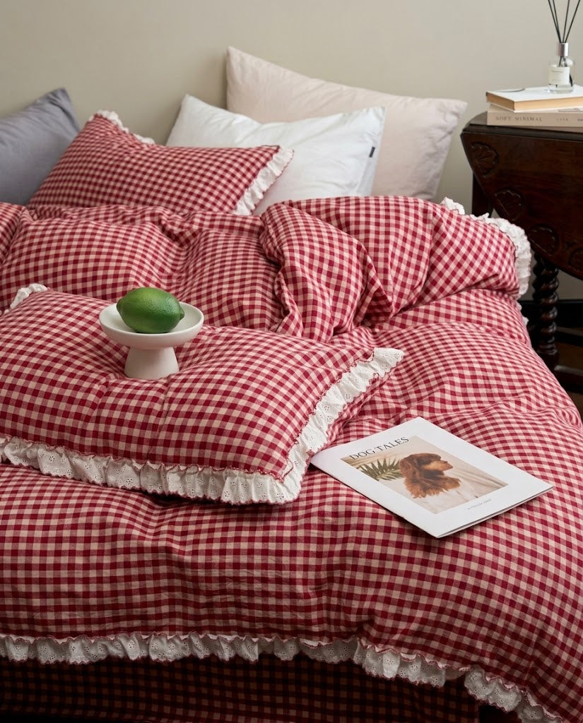 Red and cream gingham duvet cover and ruffled pillowcases on an unmade bed, styled with white and blush pillows