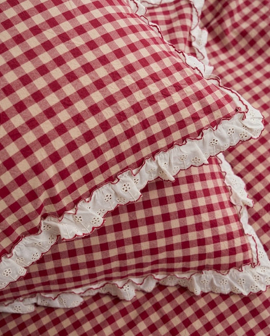 Close-up of white eyelet ruffle trim with red picot edging on washed cotton gingham pillowcases