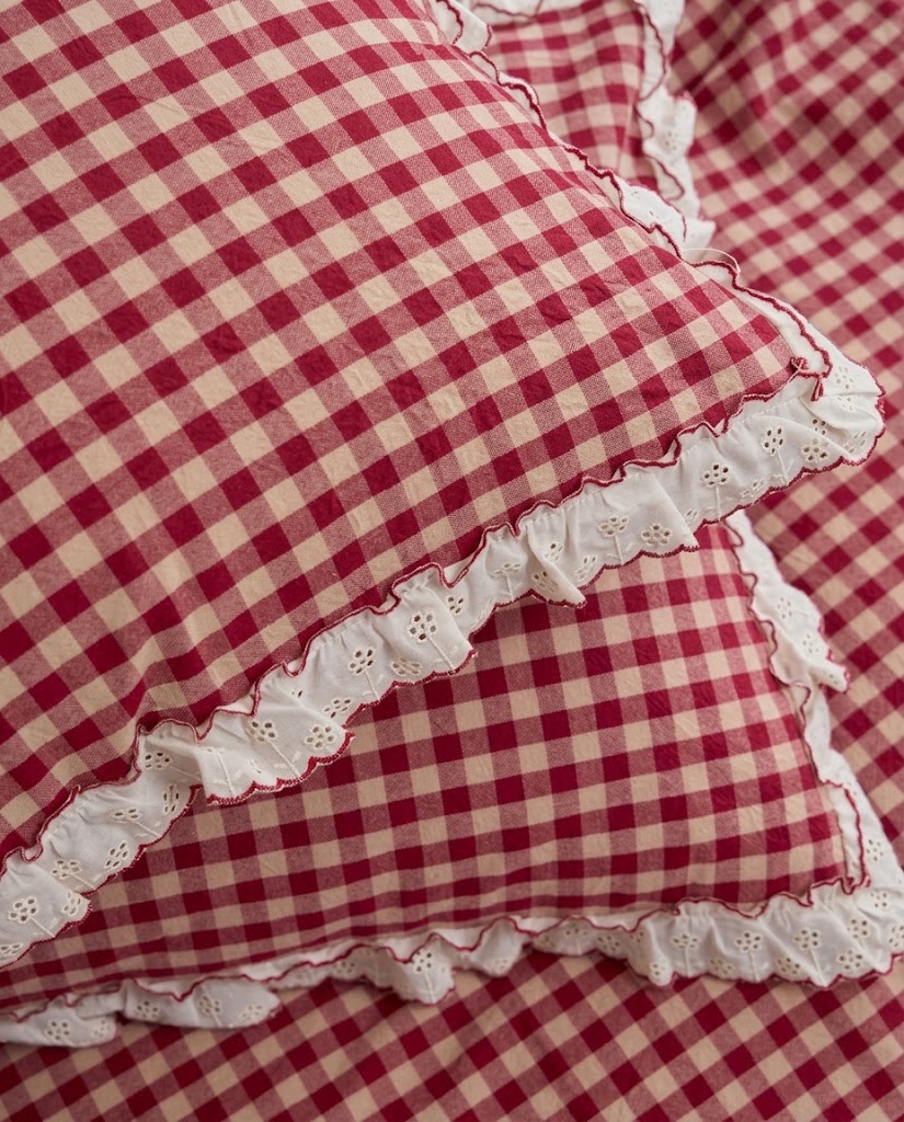 Close-up of white eyelet ruffle trim with red picot edging on washed cotton gingham pillowcases