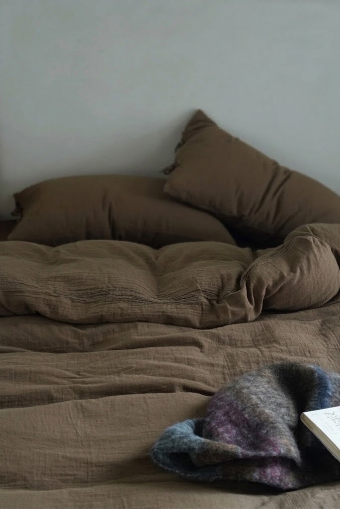 Rumpled Truffle muslin cotton duvet cover and pillowcases with a knit throw and an open book
