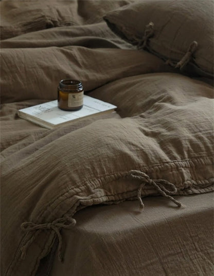 Truffle muslin duvet cover with bow tie closures and an amber candle on a book