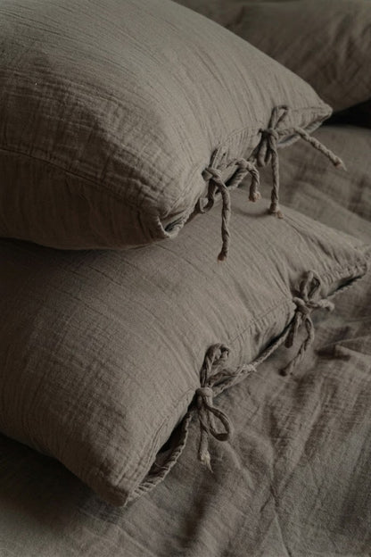 Close-up of Truffle muslin cotton pillowcases with twisted bow tie closures