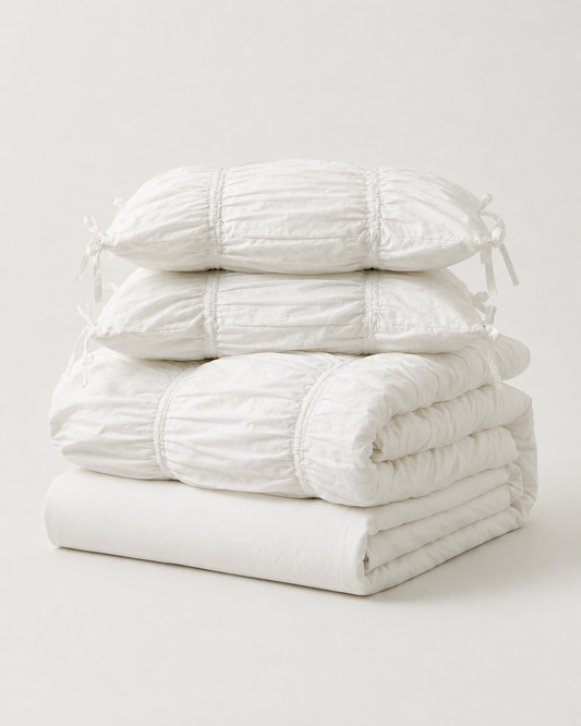 Classic White Ruched Duvet Cover Set folded and stacked, showing the duvet cover, flat sheet, and two ruched pillow shams with bow ties