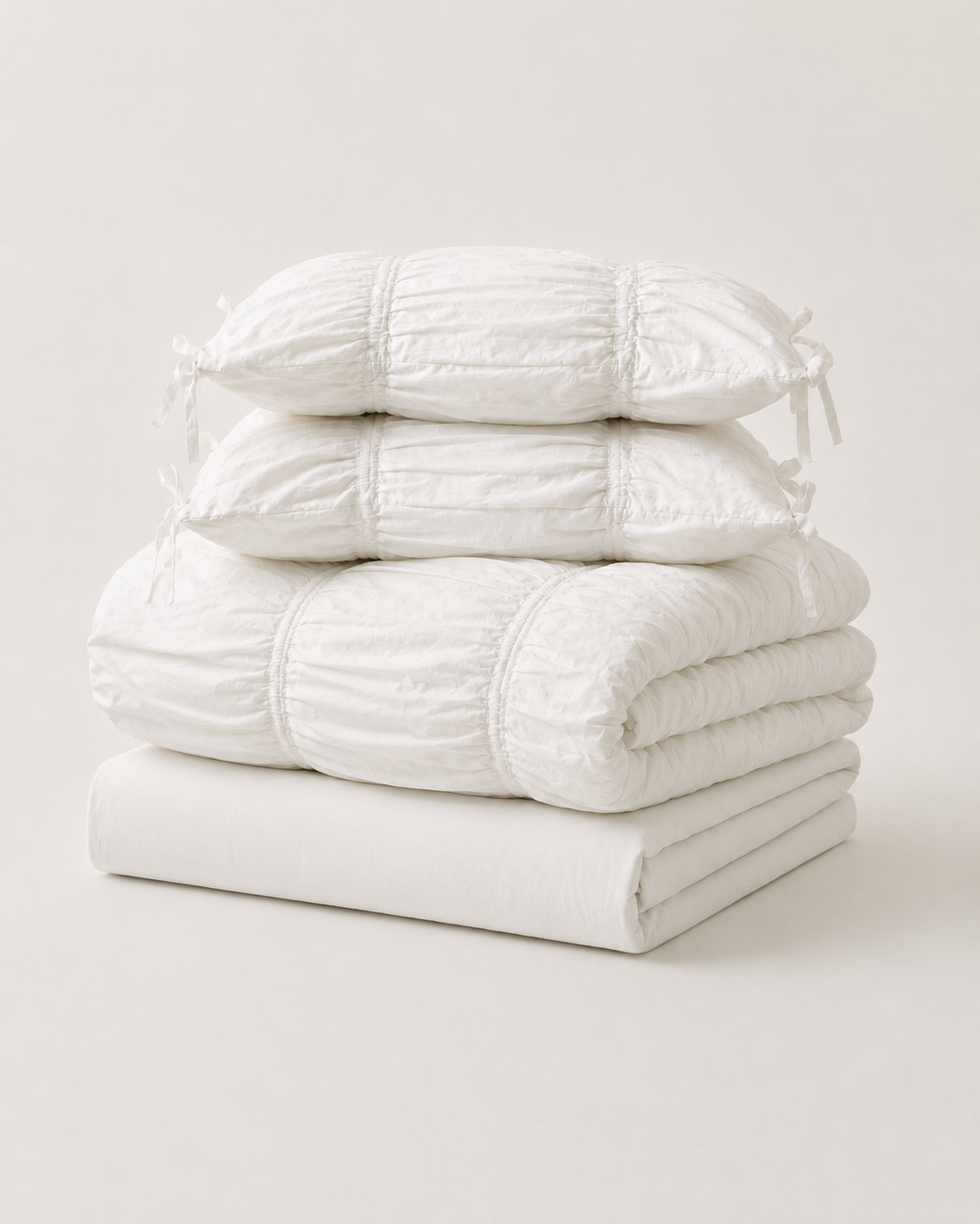 Classic White Ruched Duvet Cover Set folded and stacked, showing the duvet cover, flat sheet, and two ruched pillow shams with bow ties