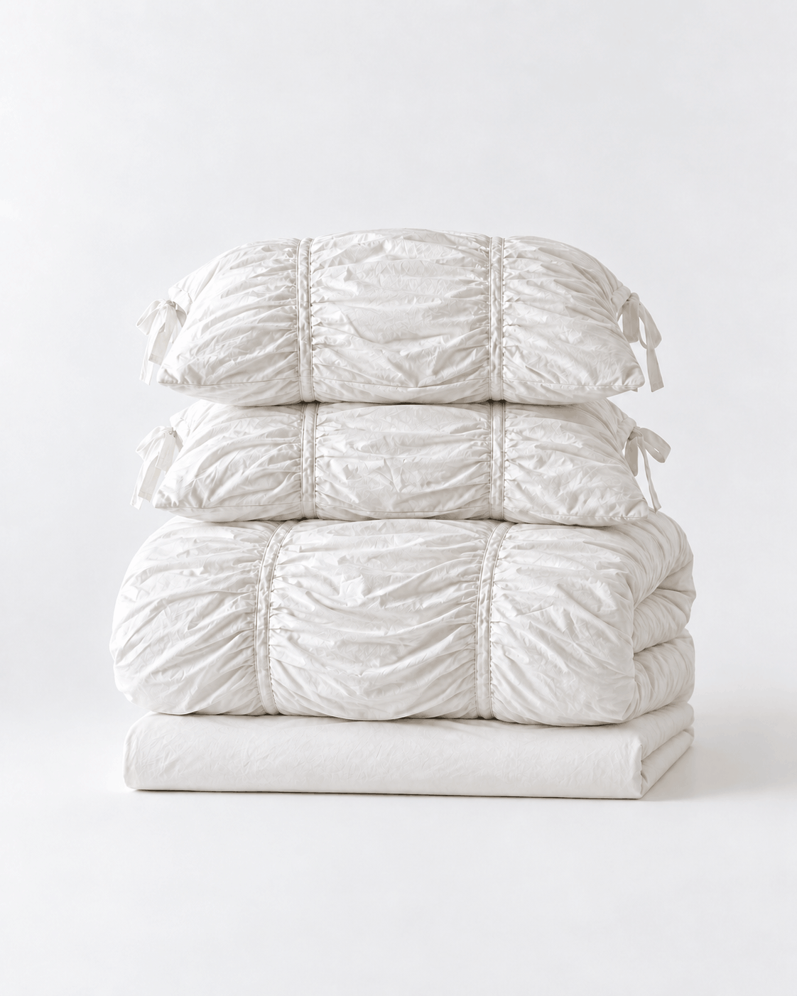 Classic White Ruched Duvet Cover Set folded and stacked, showing the duvet cover, flat sheet, and two ruched pillow shams with bow ties