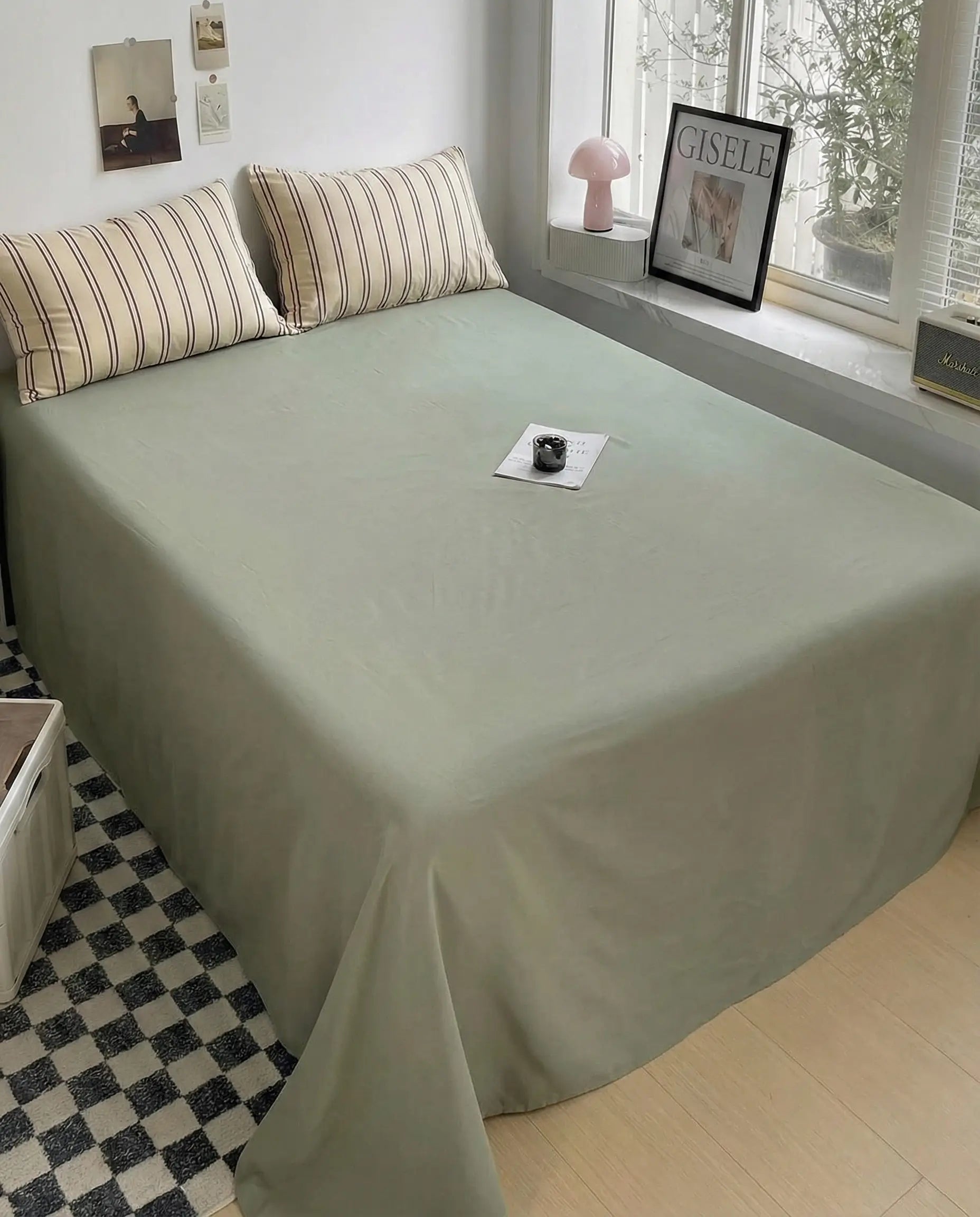 Olive green flat sheet paired with beige striped pillowcases in clean modern bedroom setup