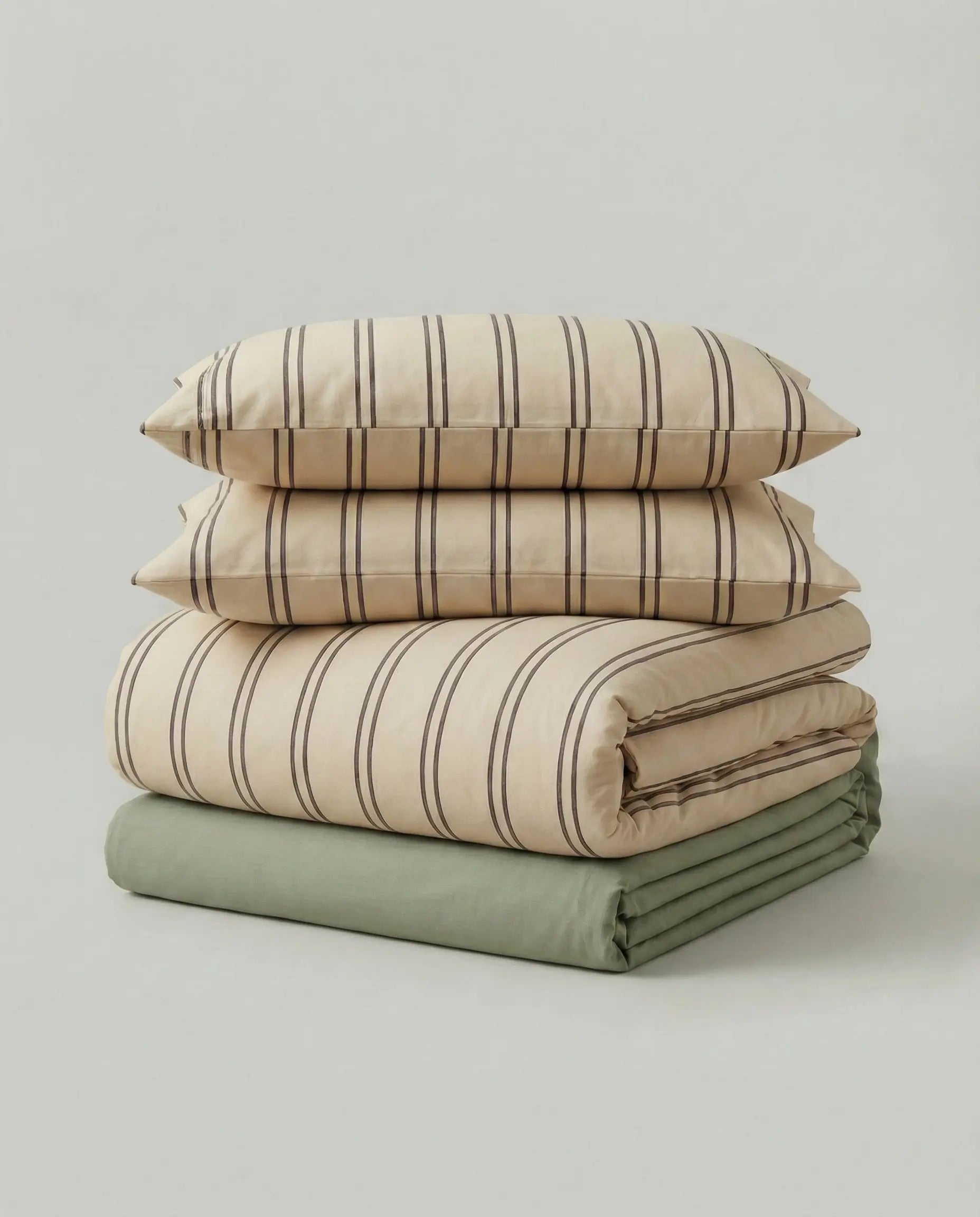 Folded beige striped bedding set with matching pillowcases and olive green sheet in studio product photo