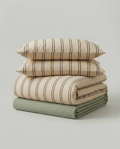 Folded beige striped bedding set with matching pillowcases and olive green sheet in studio product photo