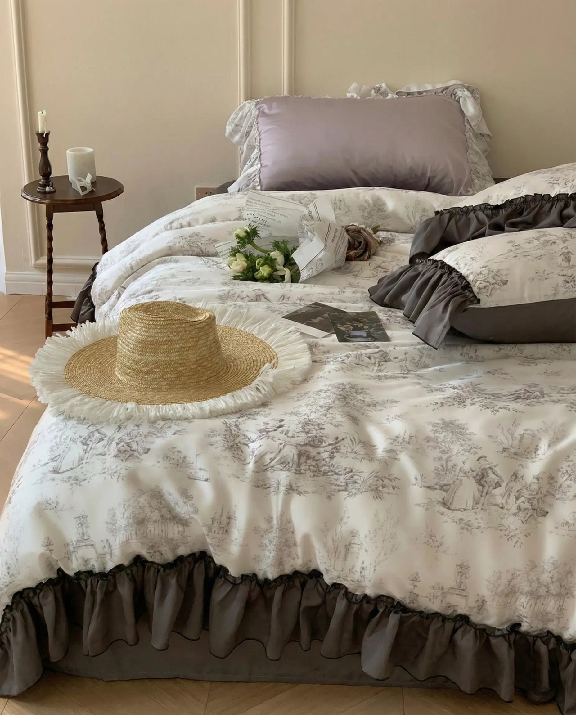 Close up of toile patterned duvet and ruffled pillow shams styled with flowers, romantic vintage bedding set