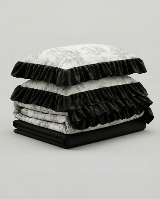 Folded toile duvet cover set stacked with matching pillowcases and dark ruffle edges, luxury cottage bedroom bedding