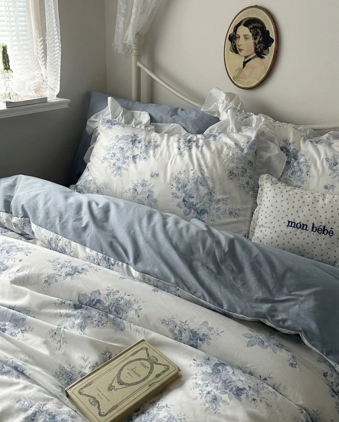 Ivory duvet cover with blue rose floral print and airy ruffle edges styled on feminine cottage bed