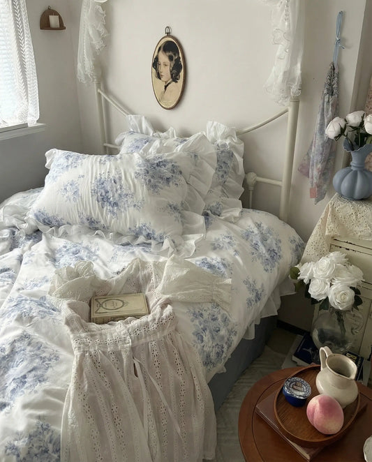 Romantic blue floral comforter with lightweight ruffle trim styled in sunlit aesthetic bedroom