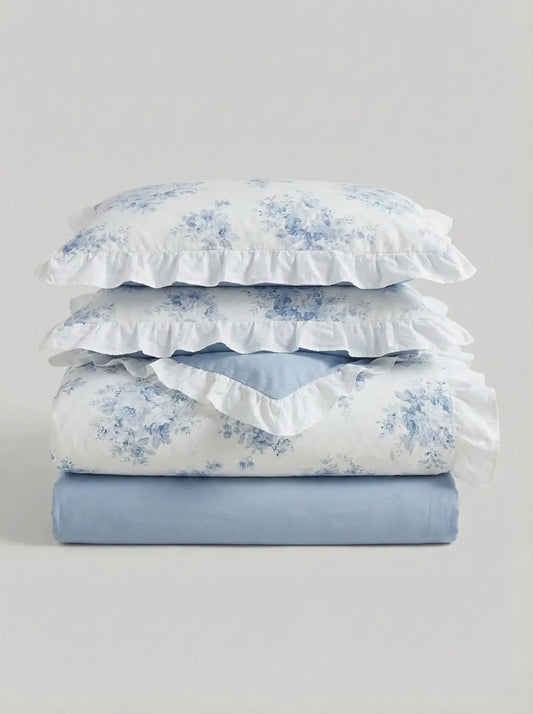 Folded blue floral ruffled duvet cover set with matching pillowcases and soft blue fitted sheet on white background