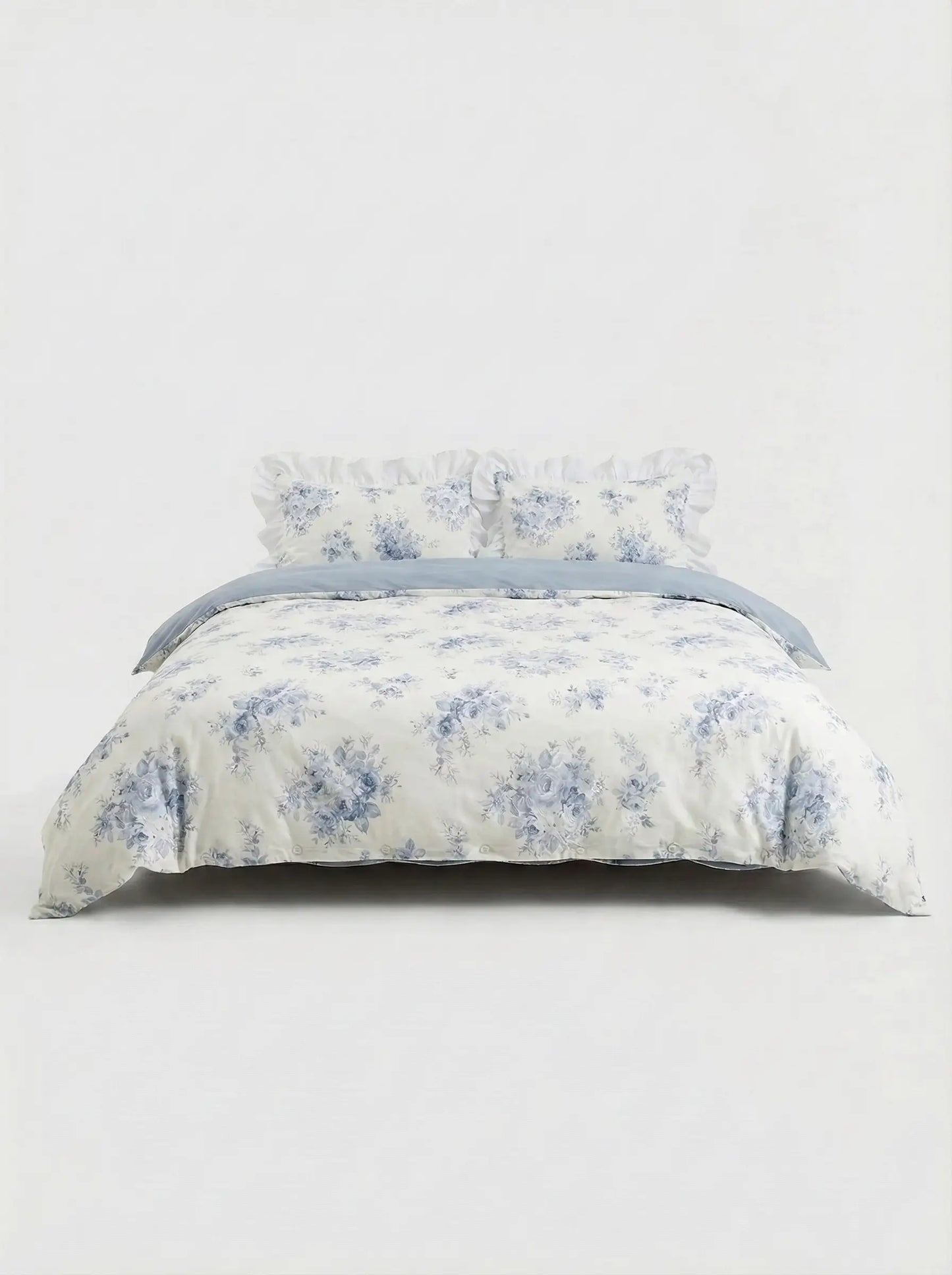 Blue floral ruffled duvet cover set with matching pillow shams styled on bed against clean white studio background