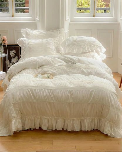 White ruched duvet cover set styled on bed with ruffled hem and layered pillows in sunlit bedroom
