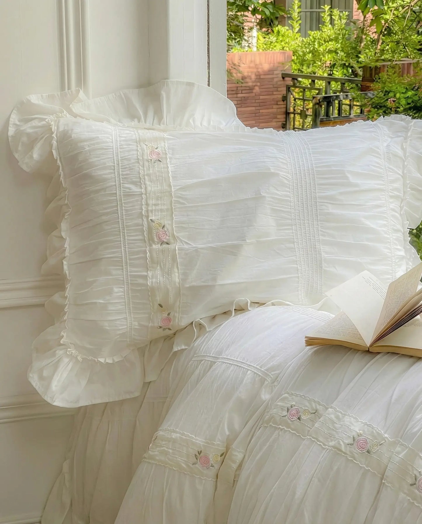 White ruched pillow sham close up with ruffle edge and delicate floral embroidery in natural light