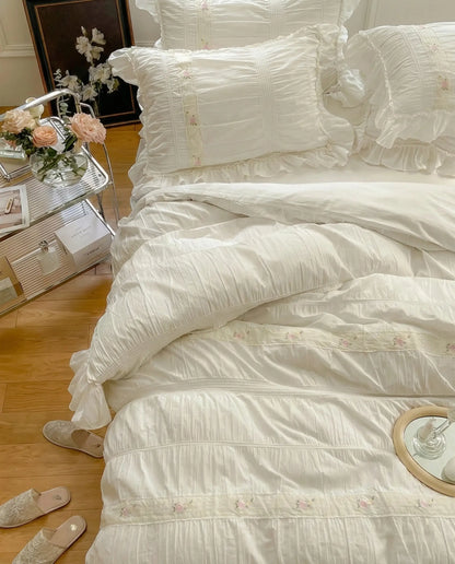 White ruched duvet cover set styled with tray and candles on bed in classic white bedroom