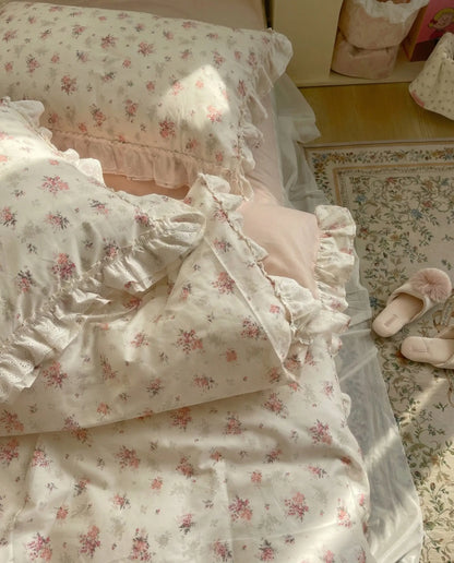 Close up of floral bedding with delicate lace ruffles and soft blush pink fitted sheet in feminine bedroom