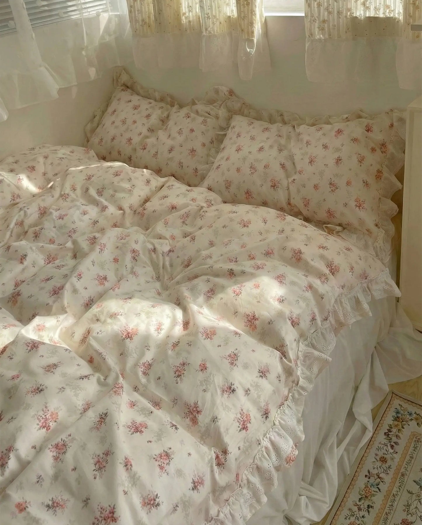 Cream floral comforter with pink rose pattern and lace ruffle detailing on cozy feminine bed