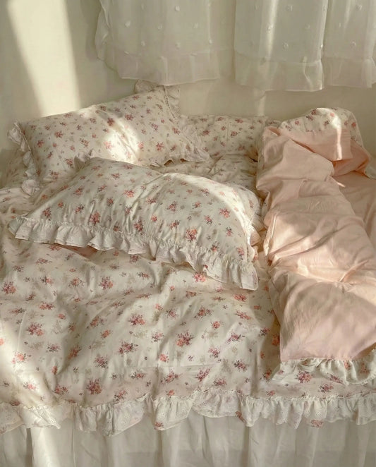 Ivory floral duvet cover with lace ruffle trim and blush pink sheets styled on cozy romantic bed