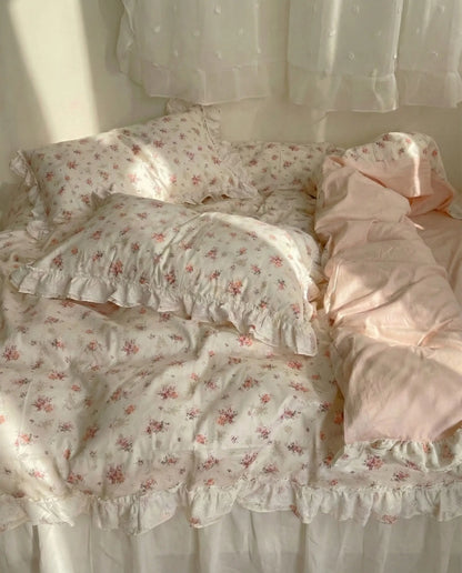 Ivory floral duvet cover with lace ruffle trim and blush pink sheets styled on cozy romantic bed