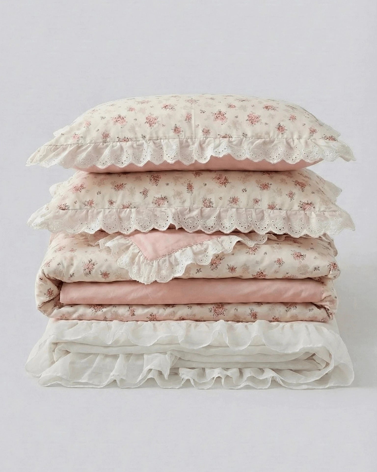 Floral duvet cover set with lace ruffle trim and blush pink sheets folded studio style product photo