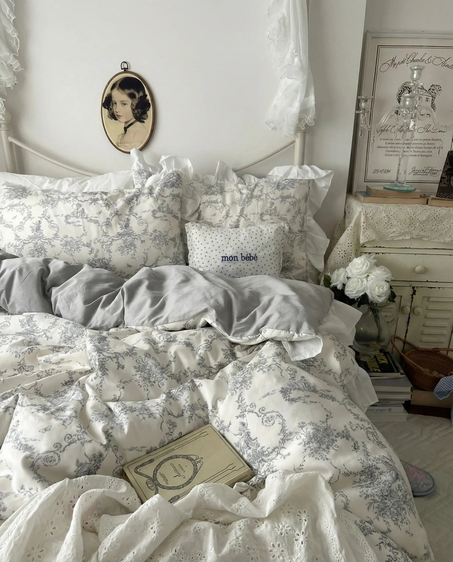 Vintage inspired bed styled with grey floral duvet, ruffled edges, books and soft neutral decor, creating a calm romantic bedroom look, aesthetic bedding, vintage bedding, floral duvet, white bedding, grey floral, cottage bedroom, bedroom decor