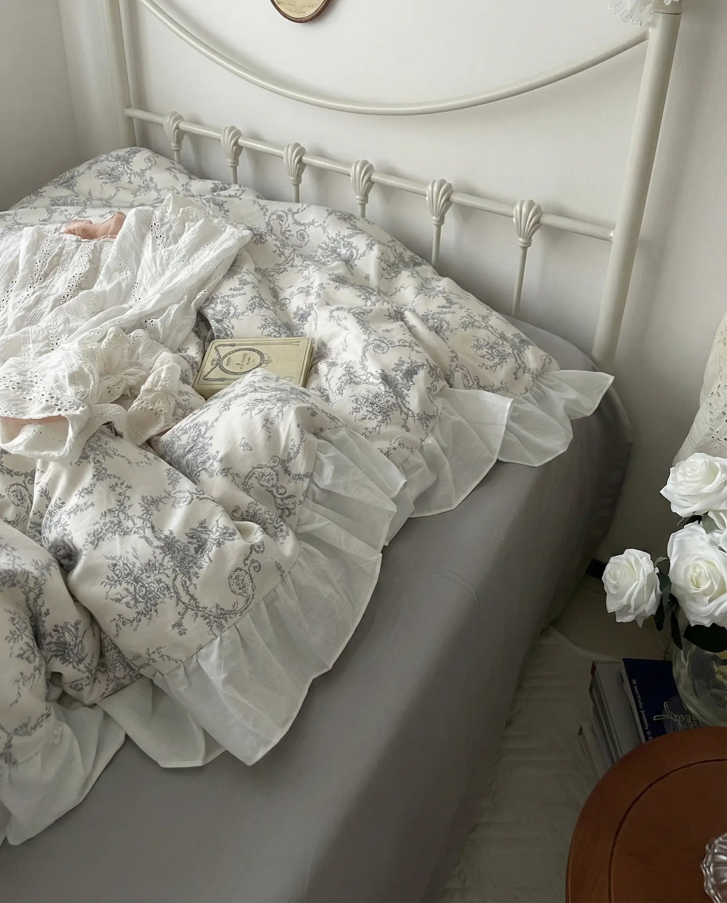 Side view of grey floral duvet cover with flowing ruffled trim over a white fitted sheet, showcasing soft drape and vintage detailing, aesthetic bedding, vintage bedding, floral duvet, white bedding, grey floral, romantic bedroom, cottage bedroom, bedroom decor