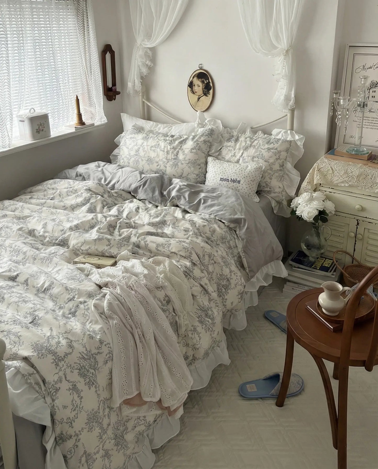 Wide shot of a white bedroom styled with a grey floral ruffled duvet cover set, layered pillows and vintage accents, aesthetic bedroom, vintage bedding, floral duvet, white bedding, grey floral, romantic bedroom, cottage bedroom, bedroom decor