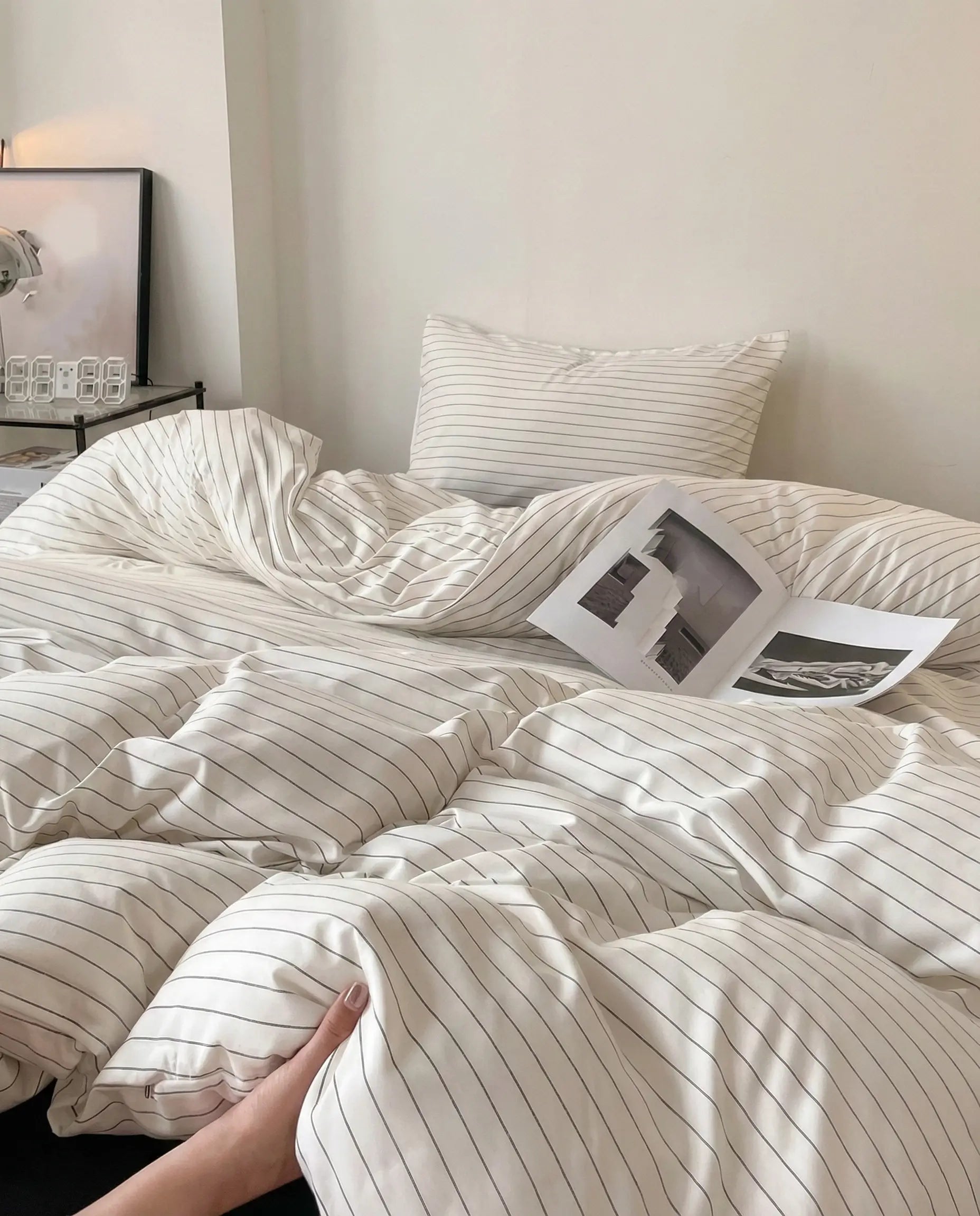 White striped bedding styled in natural daylight with soft shadows, emphasizing breathable fabric and relaxed modern design.