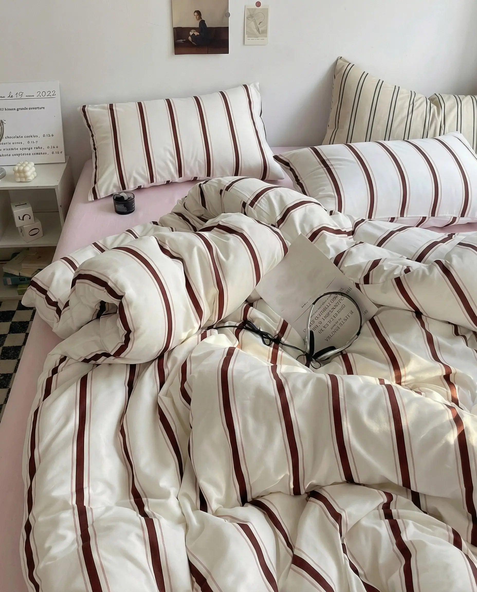 Cream duvet cover with warm brown vertical stripes styled on an unmade bed with matching striped pillowcases and soft natural light
