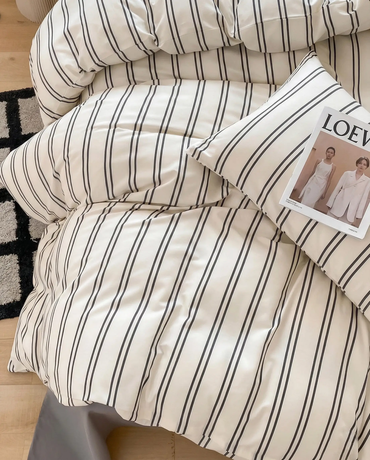 Soft striped bedding styled with layered pillows and a relaxed drape, perfect for creating an effortlessly lived-in bedroom look.