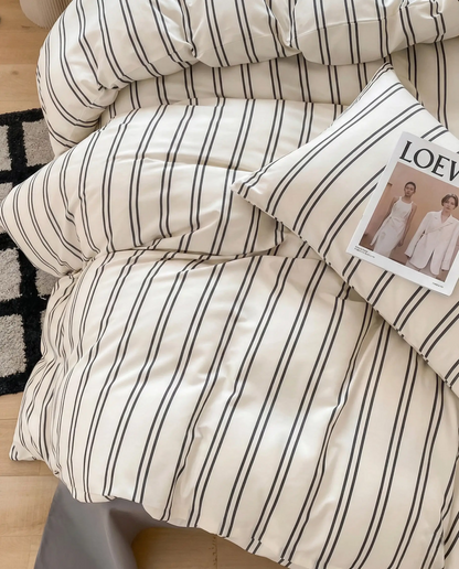 Soft striped bedding styled with layered pillows and a relaxed drape, perfect for creating an effortlessly lived-in bedroom look.