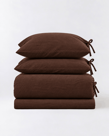 Folded Chocolate Espresso muslin cotton duvet cover set showing duvet cover, flat sheet, and two tie-closure pillowcases