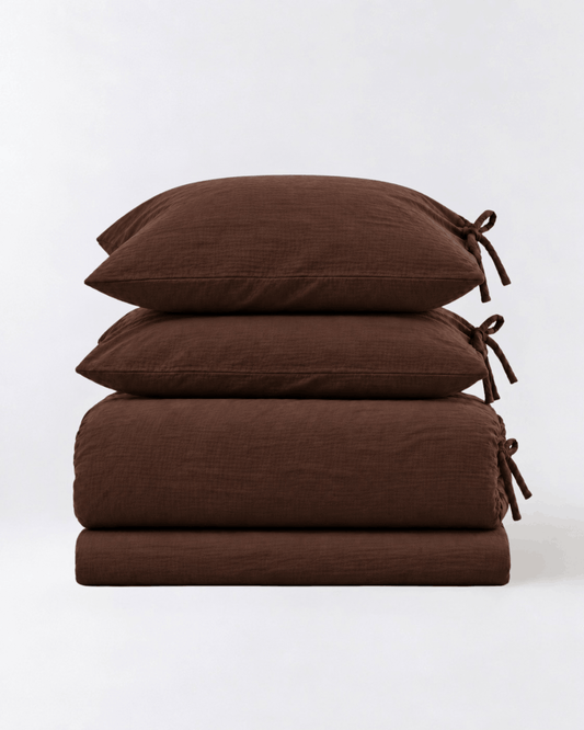 Folded Chocolate Espresso muslin cotton duvet cover set showing duvet cover, flat sheet, and two tie-closure pillowcases