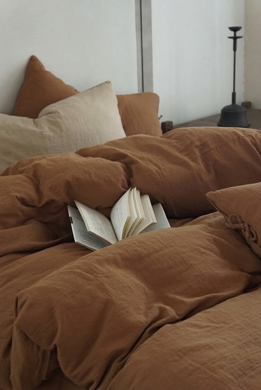 Rumpled Cinnamon crinkled muslin duvet cover with an open book and a neutral accent pillow