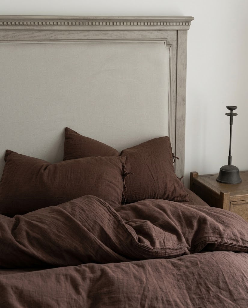 Chocolate espresso muslin cotton pillowcases and duvet cover against a carved wooden upholstered headboard