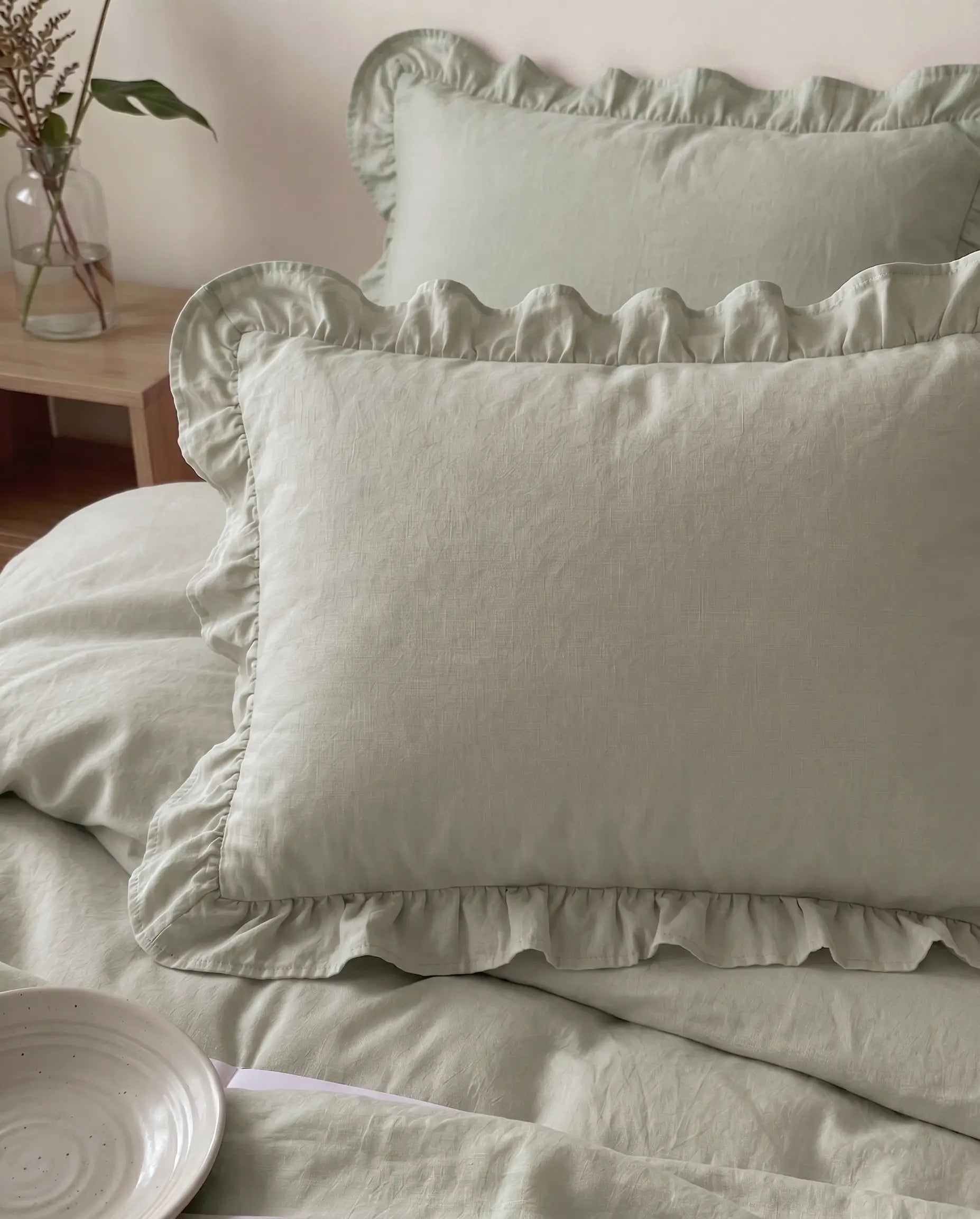 Close-up of eucalyptus sage ruffle pillow shams featuring soft cotton texture and romantic gathered trim details