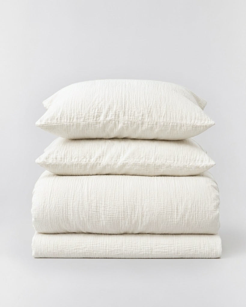 Amalfi Muslin Cotton Duvet Cover Set in Pearl, folded duvet cover and two pillowcases on light grey