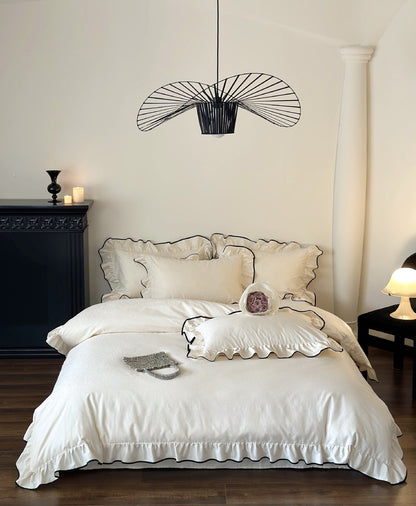 Ivory Camellia Ruffled Duvet Cover Set styled in a bedroom with black fireplace and pendant light